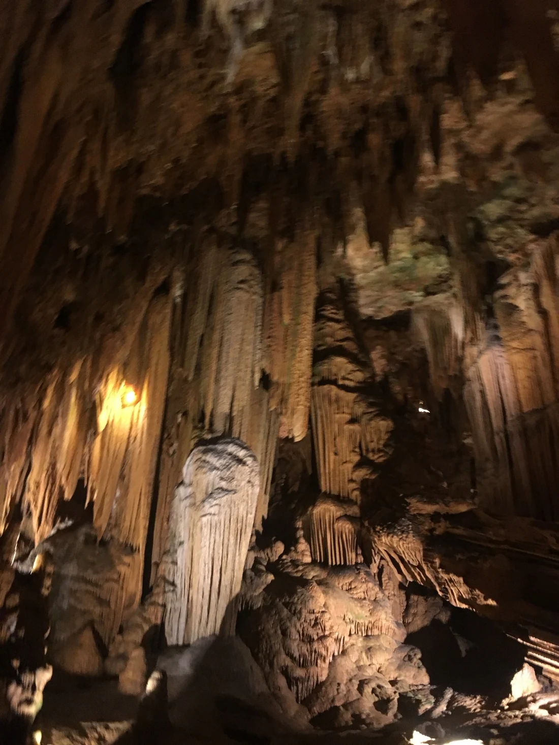 Illuminated stalactites and tall rock formations inside a cavern